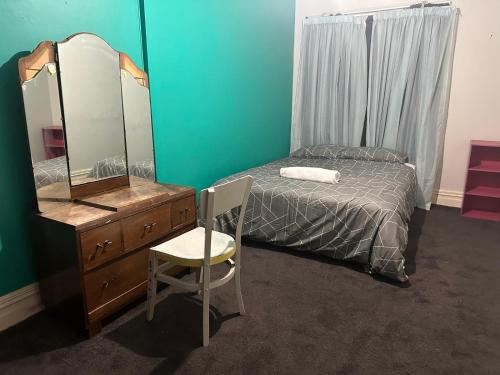 - une chambre avec un lit, une commode et un miroir dans l'établissement Railway Hotel, à South Rakaia