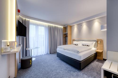 a hotel room with a bed and a television at Holiday Inn Express Göttingen by IHG in Göttingen