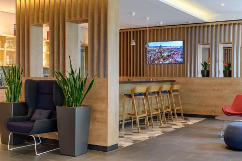 a lobby with a bar with stools and a tv at Holiday Inn Express Göttingen by IHG in Göttingen