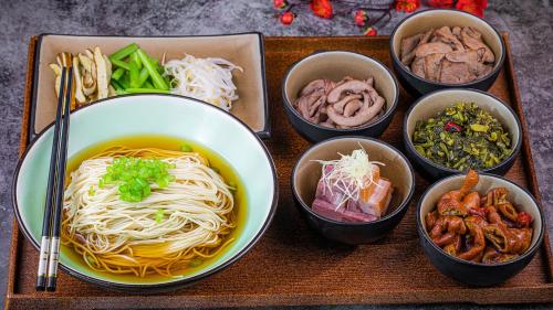 a tray with bowls of food and a bowl of noodles at Crowne Plaza Zhenjiang by IHG in Zhenjiang