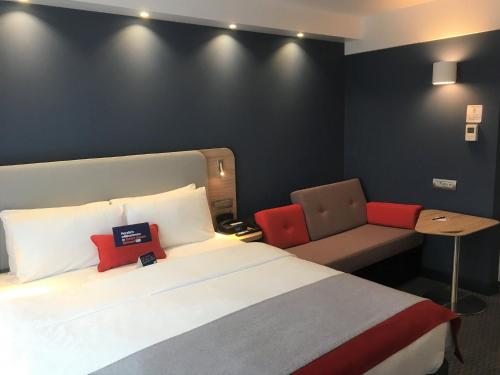 a hotel room with a bed and a chair at Holiday Inn Express Zürich Airport by IHG in Rümlang