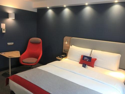 a hotel room with a bed and a red chair at Holiday Inn Express Zürich Airport by IHG in Rümlang