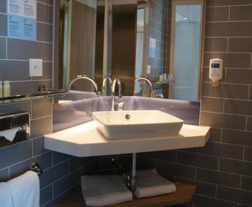 La salle de bains est pourvue d'un lavabo blanc et d'un miroir. dans l'établissement Holiday Inn Express Zürich Airport, an IHG Hotel, à Rümlang