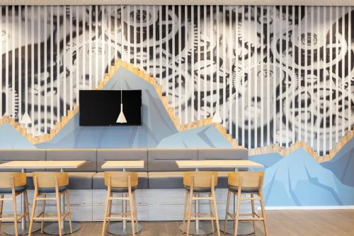 a restaurant with tables and chairs and a mural at Holiday Inn Express - Aarburg - Oftringen by IHG in Oftringen