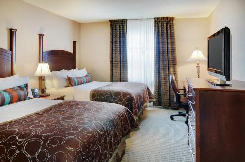 a hotel room with two beds and a flat screen tv at Staybridge Suites Oakville Burlington, an IHG Hotel in Oakville
