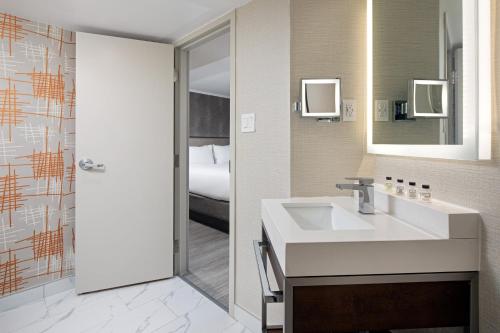 ein Bad mit einem Waschbecken, einem Spiegel und einem Bett in der Unterkunft Crowne Plaza Toronto Airport, an IHG Hotel in Toronto