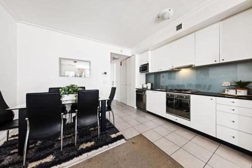 a kitchen with white cabinets and a table and chairs at A Cozy Apt for 6 Right Next to Darling Harbour in Sydney
