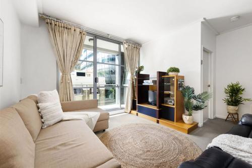 a living room with a couch and a large window at A Cozy Apt for 6 Right Next to Darling Harbour in Sydney