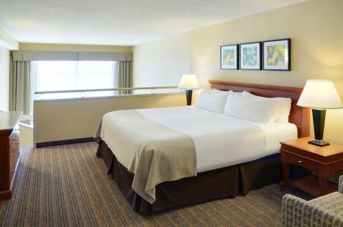 a hotel room with a large bed and a chair at Holiday Inn Hotel & Suites London, an IHG Hotel in London