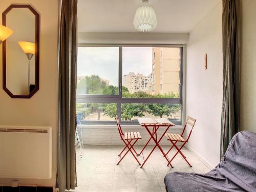 un salon avec une table et des chaises et une fenêtre dans l'établissement Charmant 2 pièces rénové proche plage avec loggia vitrée, TV, local vélos et parking - FR-1-715-66, à Mauguio