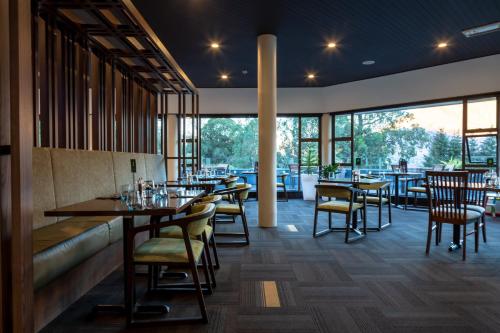 a restaurant with tables and chairs and large windows at Holiday Inn Queenstown Frankton Road, an IHG Hotel in Queenstown