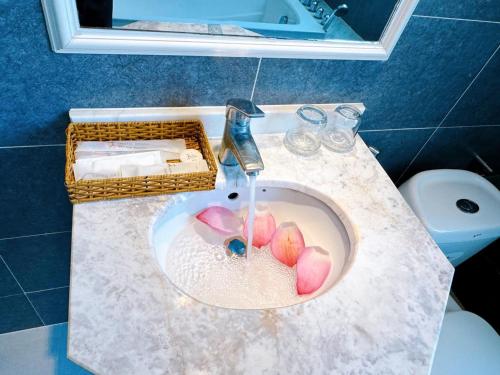 een wastafel in de badkamer met water uit een kraan bij Aodai Inn Saigon in Ho Chi Minh-stad