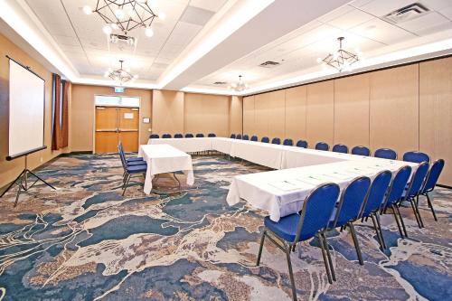 a conference room with a table and chairs and a screen at Holiday Inn Hotel & Suites - Calgary Airport North by IHG in Calgary