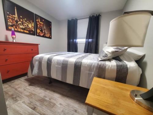 a bedroom with a bed with a lamp and a dresser at Central Private 1BR Apt. w/Free Prkg + Fast Wi-Fi in Sault Ste. Marie