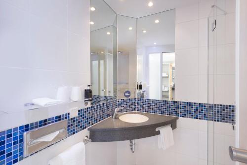 ein Bad mit einem Waschbecken und einem Spiegel in der Unterkunft Holiday Inn Express Singen, an IHG Hotel in Singen