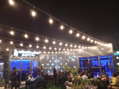 a group of people sitting at a restaurant under lights at Bristol 9 Lodge grill and bar in Abuja