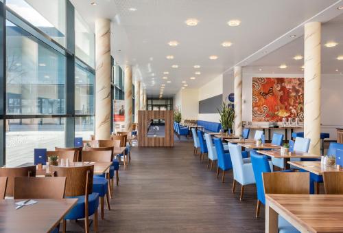 Holiday Inn Express Singen, an IHG Hotel في سينجين: غرفة طعام مع طاولات خشبية وكراسي زرقاء