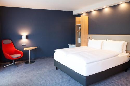 a hotel room with a bed and a red chair at Holiday Inn Express - Göppingen by IHG in Göppingen