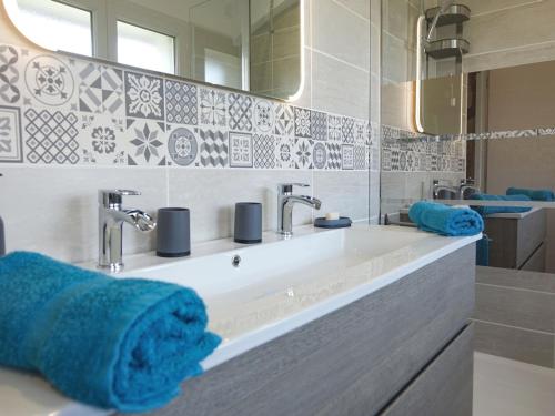 W łazience znajduje się umywalka, lustro i niebieskie ręczniki. w obiekcie Maison Saint-Gildas-de-Rhuys, 4 pièces, 6 personnes - FR-1-639-112 w mieście Saint-Gildas-de-Rhuys