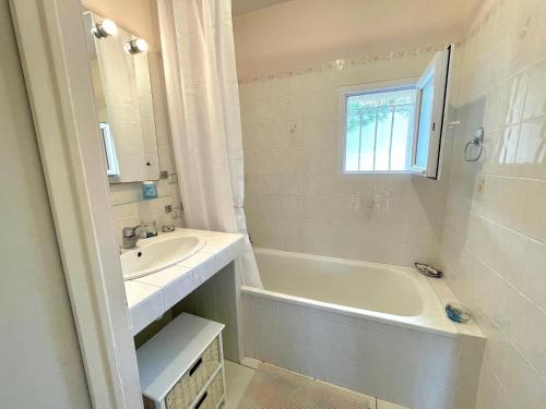 La salle de bains blanche est pourvue d'un lavabo, d'une baignoire et d'une fenêtre. dans l'établissement Maison rénovée avec jardin, 2 chambres, WiFi, à 500m de la mer - Brétignolles-sur-Mer - FR-1-231-320, à Bretignolles-sur-Mer