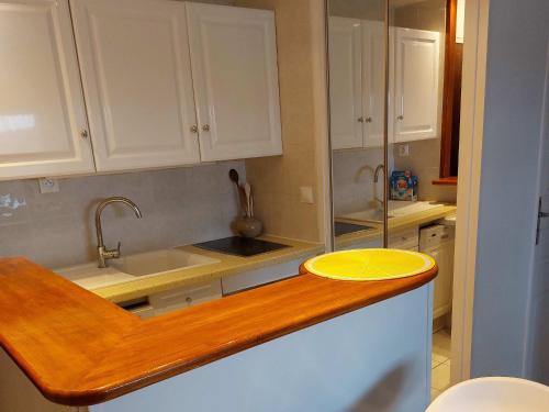 une cuisine avec des placards blancs et un bol jaune sur un comptoir dans l'établissement Charmant 2 pièces rénové avec loggia, à deux pas de la plage - Parking privé - Idéalement situé - FR-1-712-77, à Villers-sur-Mer