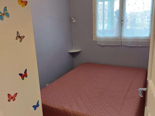 Cette petite chambre comprend un lit avec des papillons sur le mur. dans l'établissement Charmant 2 pièces rénové avec loggia, à deux pas de la plage - Parking privé - Idéalement situé - FR-1-712-77, à Villers-sur-Mer