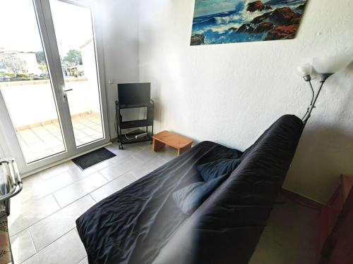 un salon avec un canapé et une télévision dans l'établissement Charmant Studio Mezzanine pour 4 avec Terrasse en Pleine Pinède, à 900m de la Plage - FR-1-607-191, au Cap d'Agde