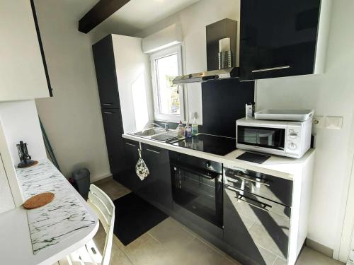 une petite cuisine avec un évier et un micro-ondes dans l'établissement Charmant Studio Mezzanine pour 4 avec Terrasse en Pleine Pinède, à 900m de la Plage - FR-1-607-191, au Cap d'Agde