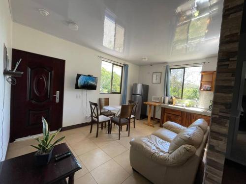 ein Wohnzimmer mit einem Sofa und einem Tisch sowie eine Küche in der Unterkunft Esparza-PURA VIDA-Tu espacio tranquilo y acogedor. in Esparza