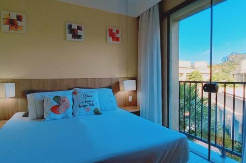 a bedroom with a bed and a large window at Flat Amo Piscina Quartier Aldeia das Águas in Barra do Piraí