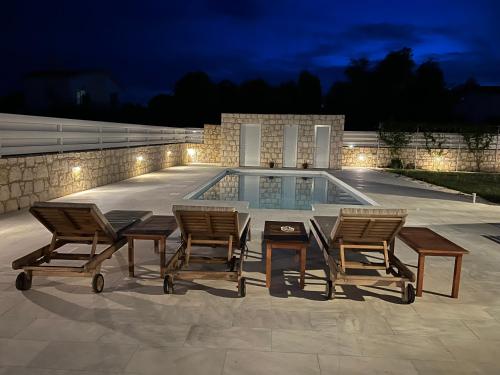 a group of chairs and a table next to a swimming pool at Jomavi Beach Eco-Villa in Polis Chrysochous