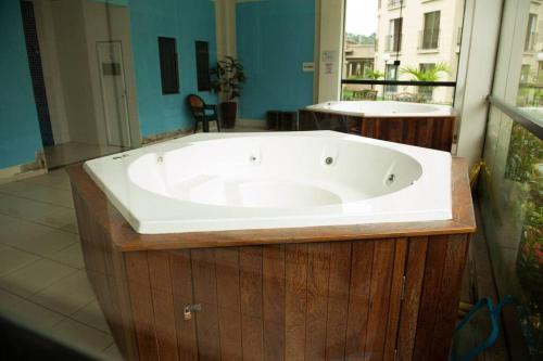 a large bath tub in a bathroom with a window at Flat Amo Piscina Quartier Aldeia das Águas in Barra do Piraí