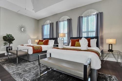 a bedroom with two beds and a chair and windows at Luxury 8-BR with Pool Basketball Volleyball in Plantation