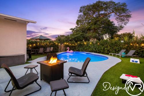 a backyard with a fire pit and chairs and a pool at 4BR retreat w heated pool backyard BBQ grill in Dania Beach