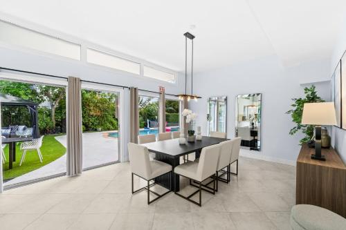 a dining room with a black table and white chairs at Family retreat wheated pool game room in West Palm Beach