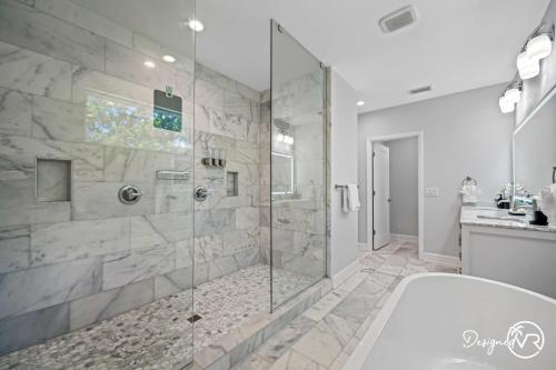 a bathroom with a tub and a glass shower at Luxury Tampa Home w Pool Jacuzzi & Amenities in Tampa
