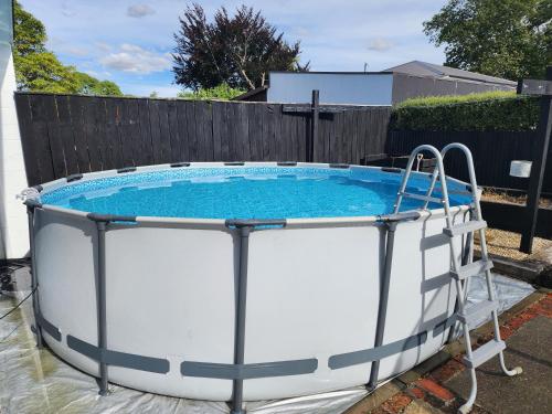 a large hot tub in a yard with a fence at Central Masterton Sleepout in Masterton