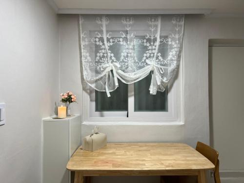 Una mesa en una habitación con una ventana con una cortina en Gongdeok Stay, en Seúl