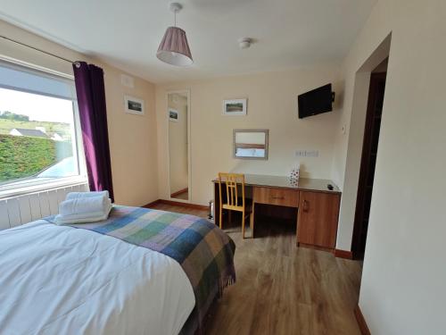 a bedroom with a bed and a desk and a window at Mountain View Accommodation in Donegal