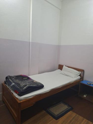 a small bed in a room with white walls at MAYUR HOTEL in Dimāpur