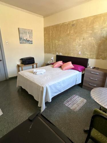 Un dormitorio con una cama con almohadas rosas. en HOSTAL LAS GARZAS, en Talara
