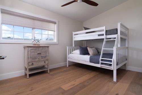 a bedroom with a white bunk bed and a wooden floor at 202 Waiehu Beach in Wailuku