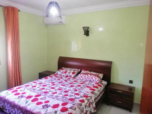 een slaapkamer met een bed met rode bloemen erop bij Mini villa duplex in Agadir