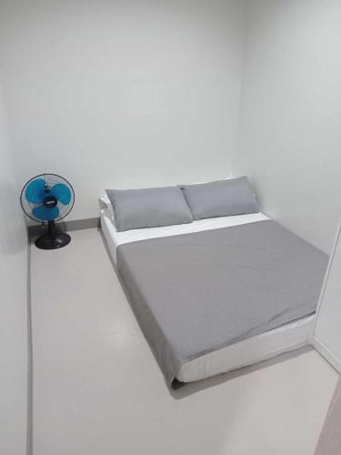 Cama en habitación blanca con ventilador azul en Casa Humilde at SMDC Charm Residences, en Manila