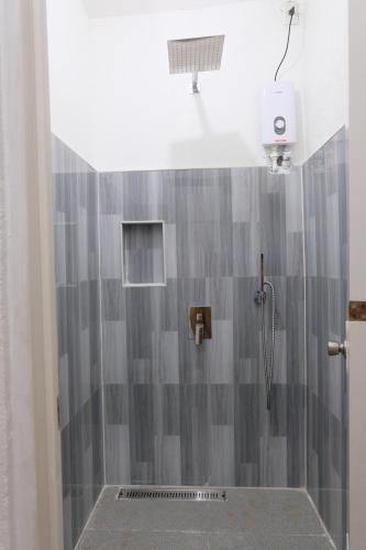 y baño con ducha y pared de azulejos grises. en Dani's House Pod Coron en Corón