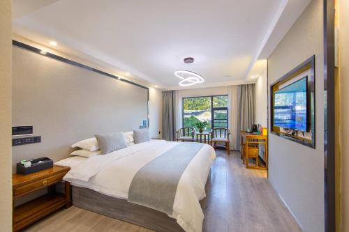 um quarto com uma cama, uma secretária e uma janela em Sochi Smart Resort Zhangjiajie em Zhangjiajie