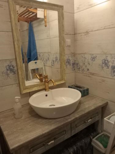 een badkamer met een witte wastafel en een spiegel bij Drewniana chatka in Budy Stare
