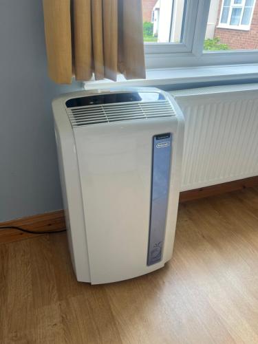 a heater sitting on the floor next to a window at Cosy 4 bedroom holiday let Stevenage 22mins from London on the train in Stevenage