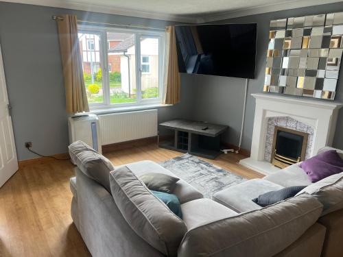 a living room with a couch and a fireplace at Cosy 4 bedroom holiday let Stevenage 22mins from London on the train in Stevenage