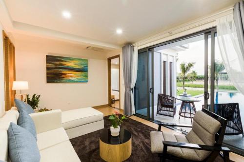 a living room with a white couch and a large window at NiNa COASTART HỒ TRÀM in Vung Tau